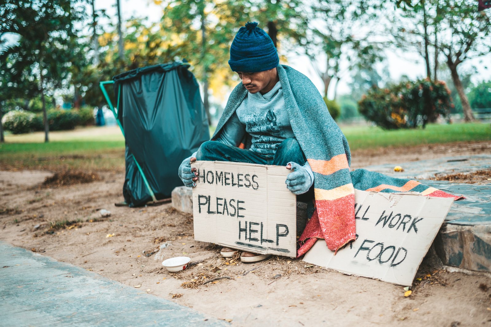 a man sitting beggars with homeless please help message. Selective focus.